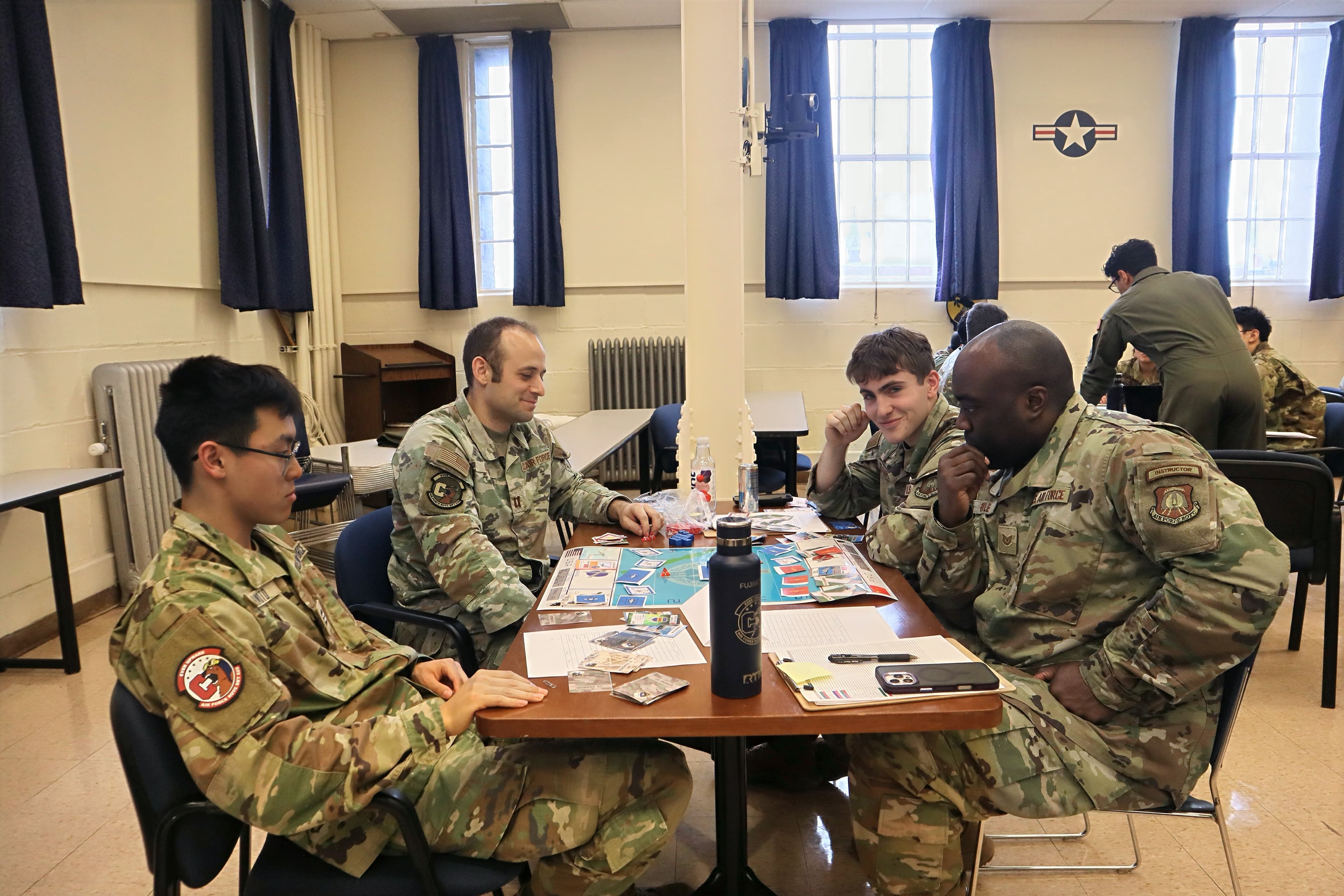 Cadre and cadets seated around a classroom table working together during a detachment exercise.