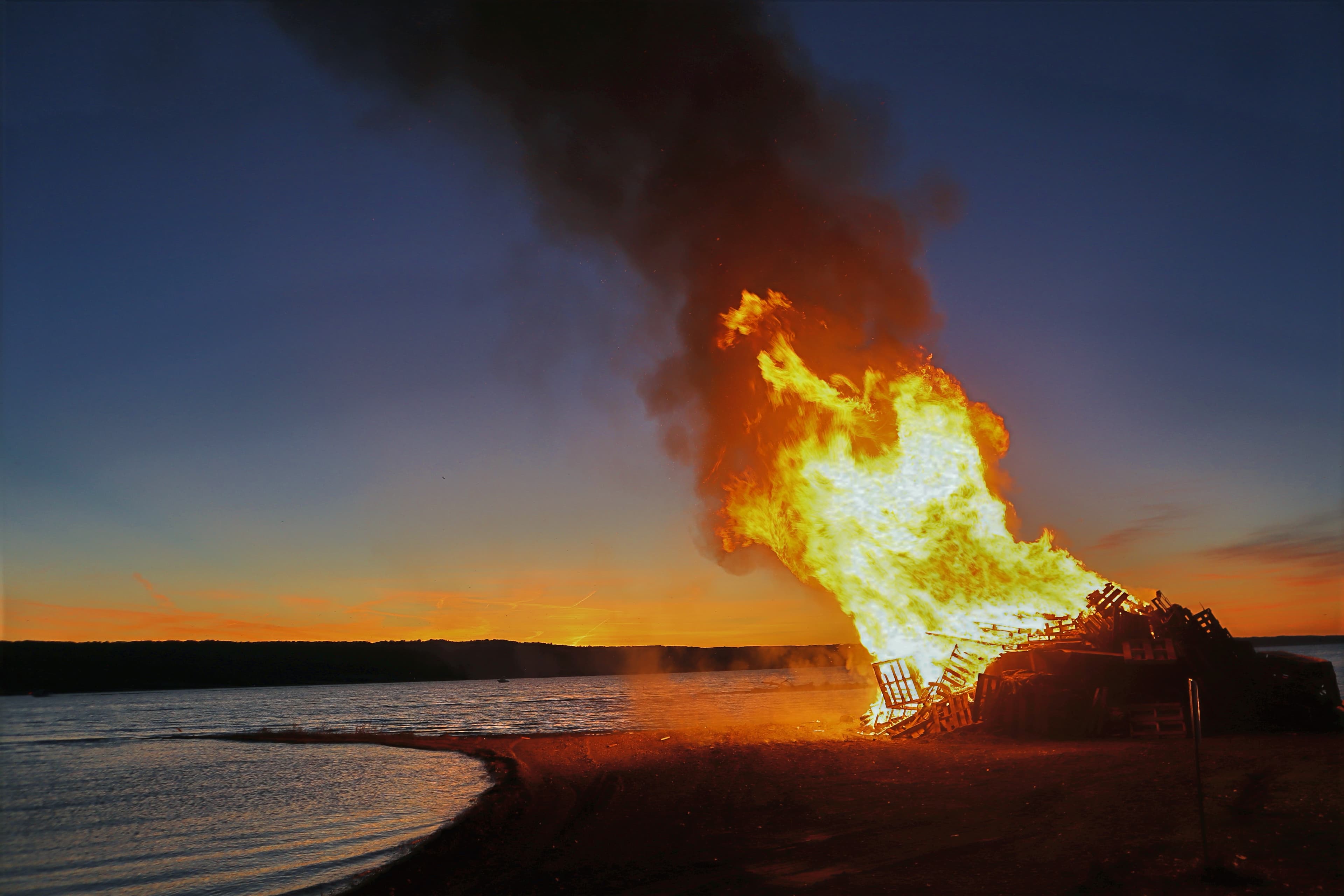 A wide view of the Watchfire burning on the lakeshore at sunset.