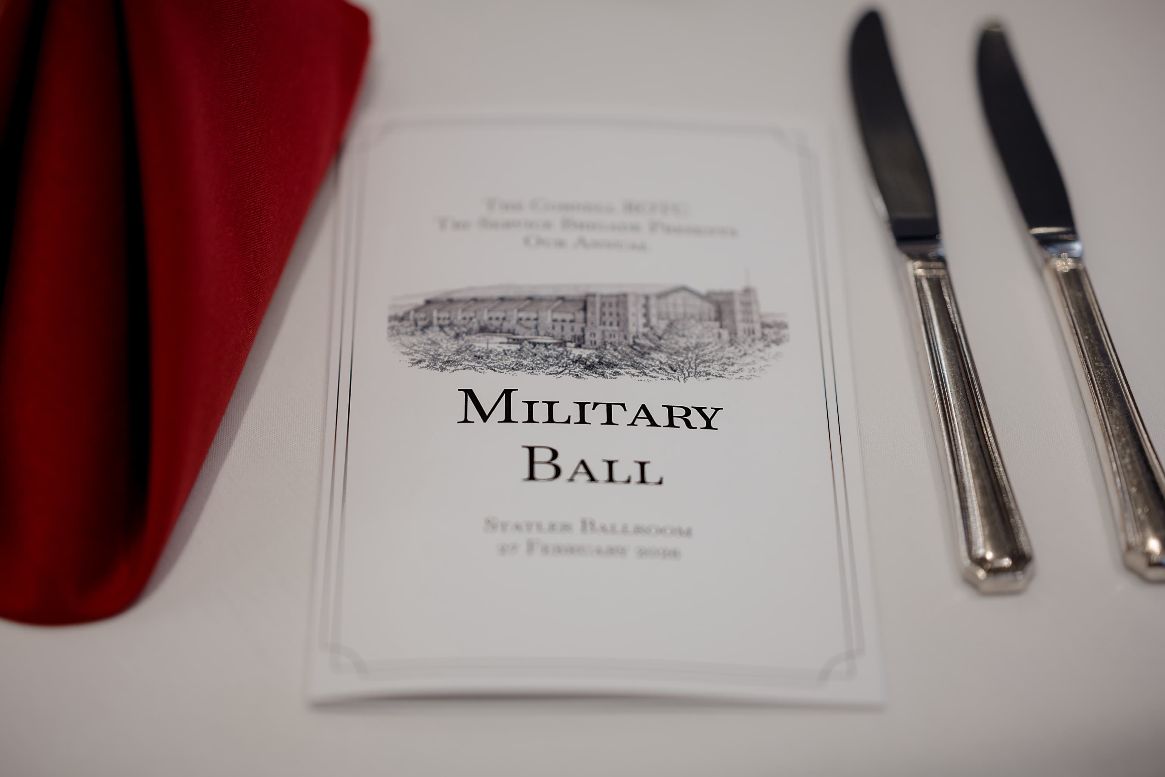 A printed Military Ball program card beside silverware on a set table.