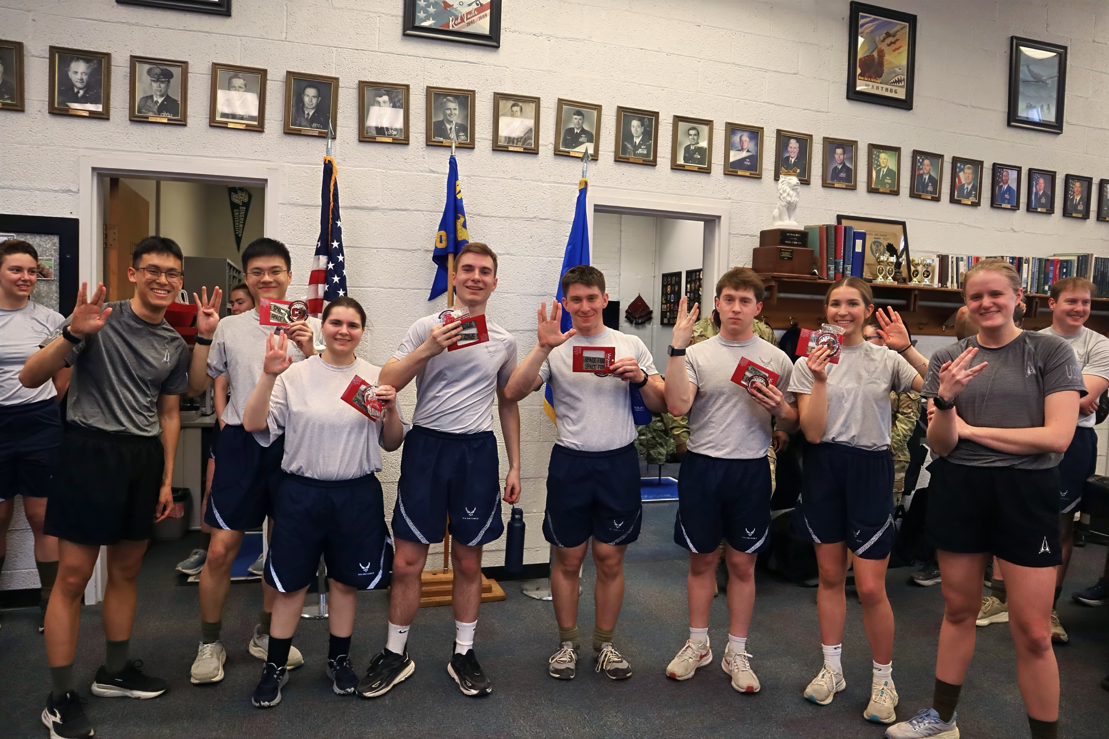 Cadets in physical training gear hold small red boxes in the detachment heritage room.