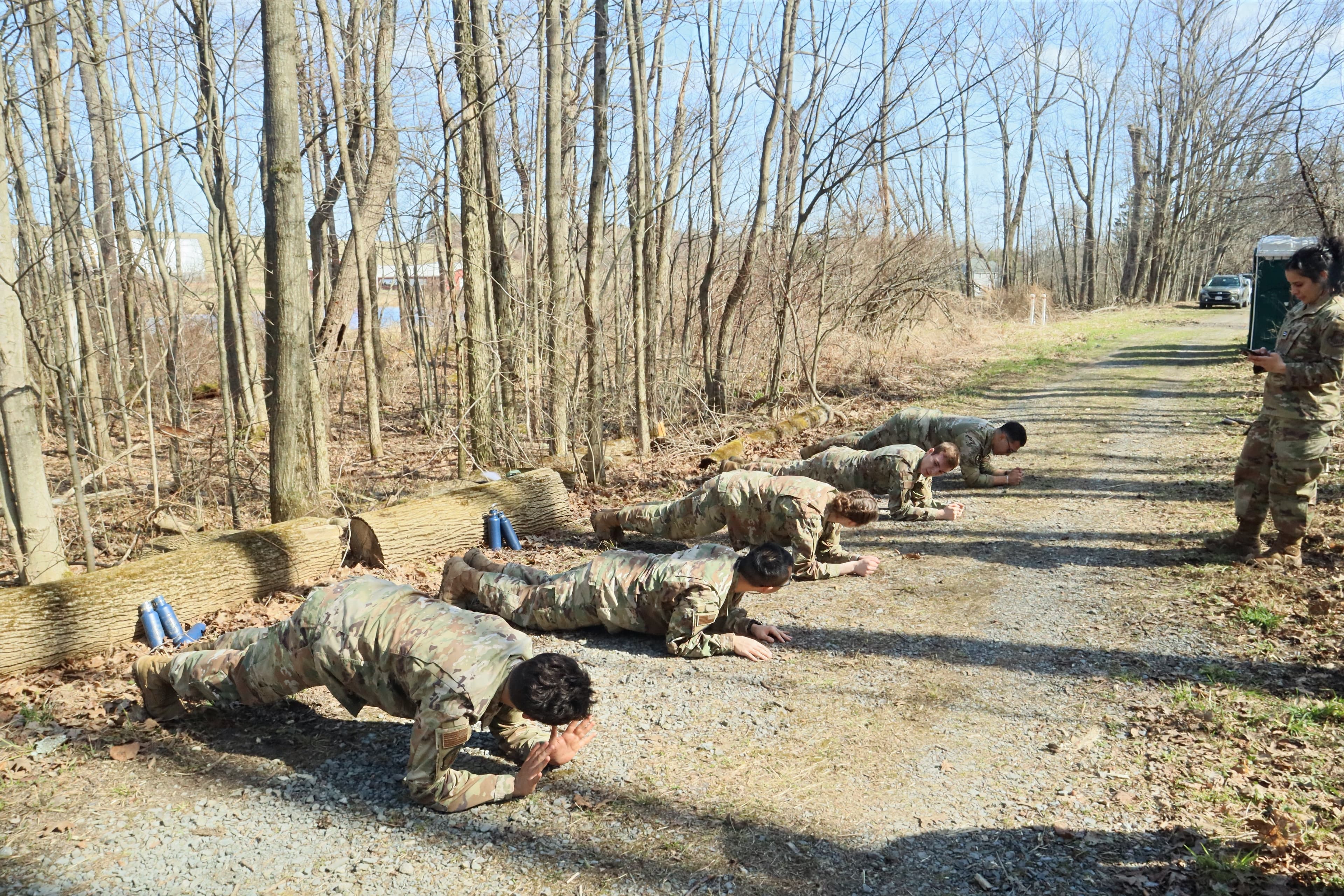 Cadets hold planks on a gravel trail during field physical training.