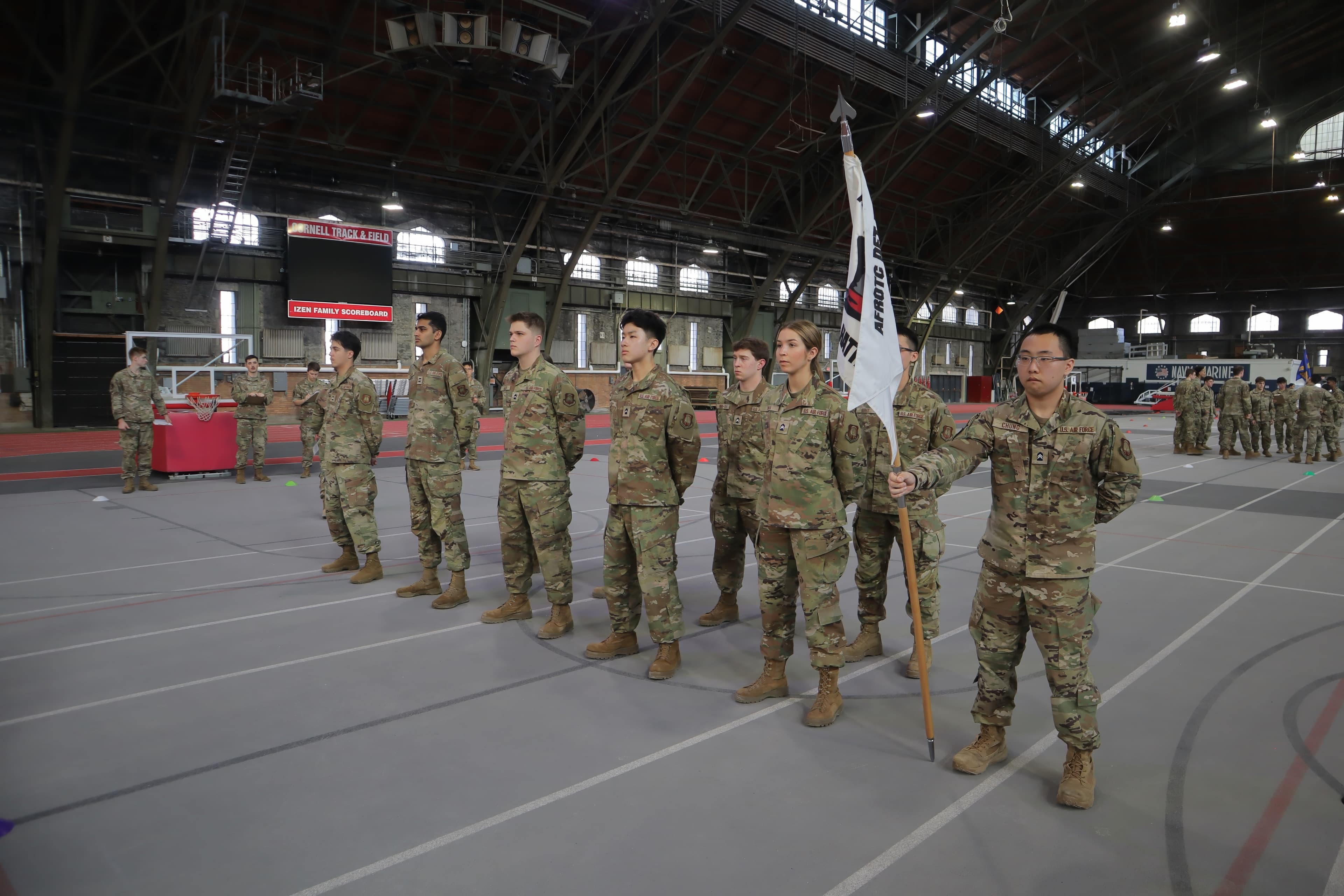 A flight of cadets stands at parade rest with a guidon in Barton Hall.