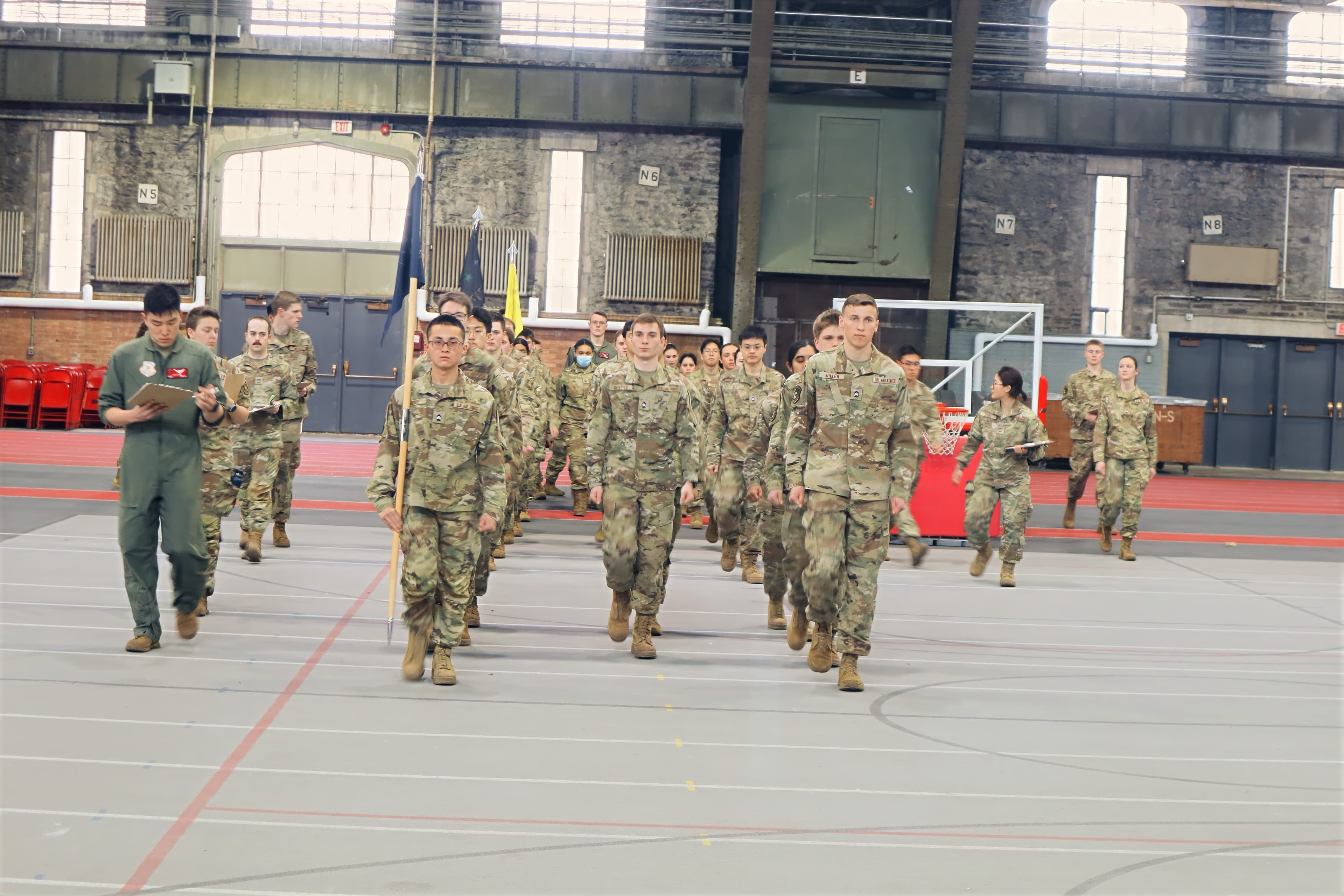 A marching column of cadets approaches the camera in Barton Hall.