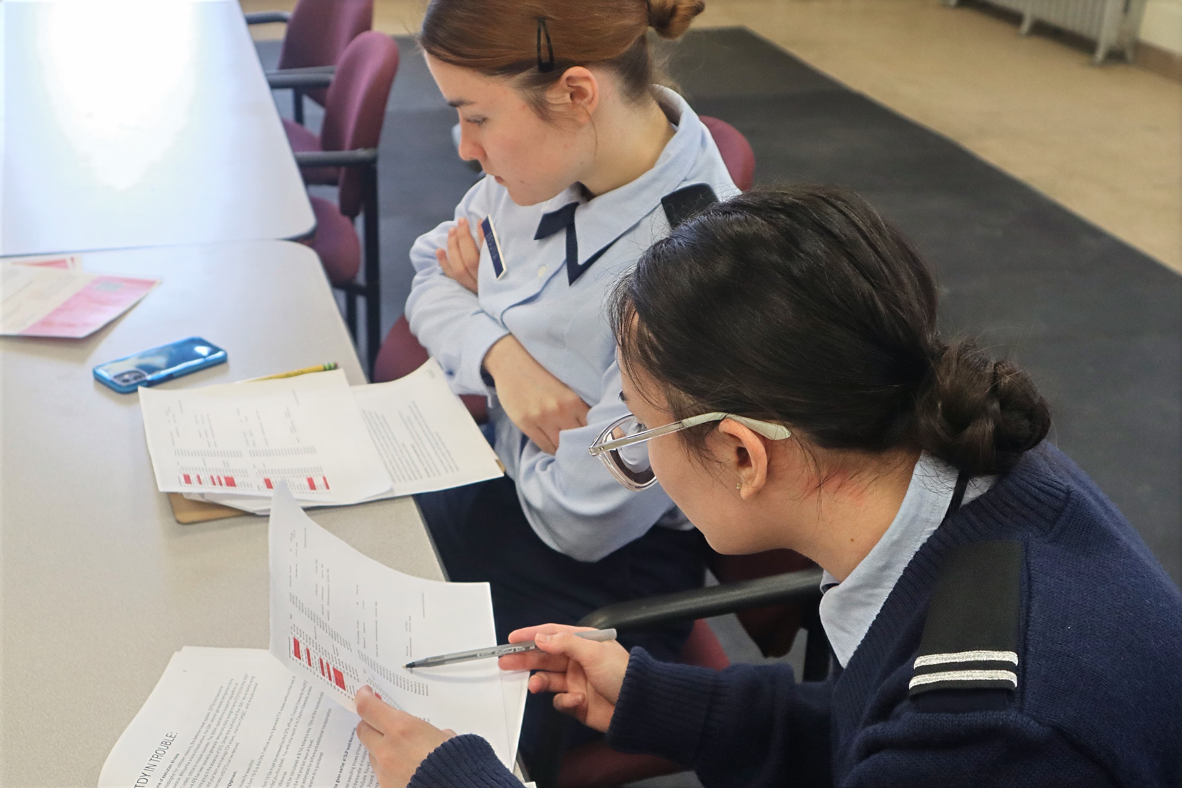 Two cadets in service dress reviewing planning paperwork together at a detachment desk.
