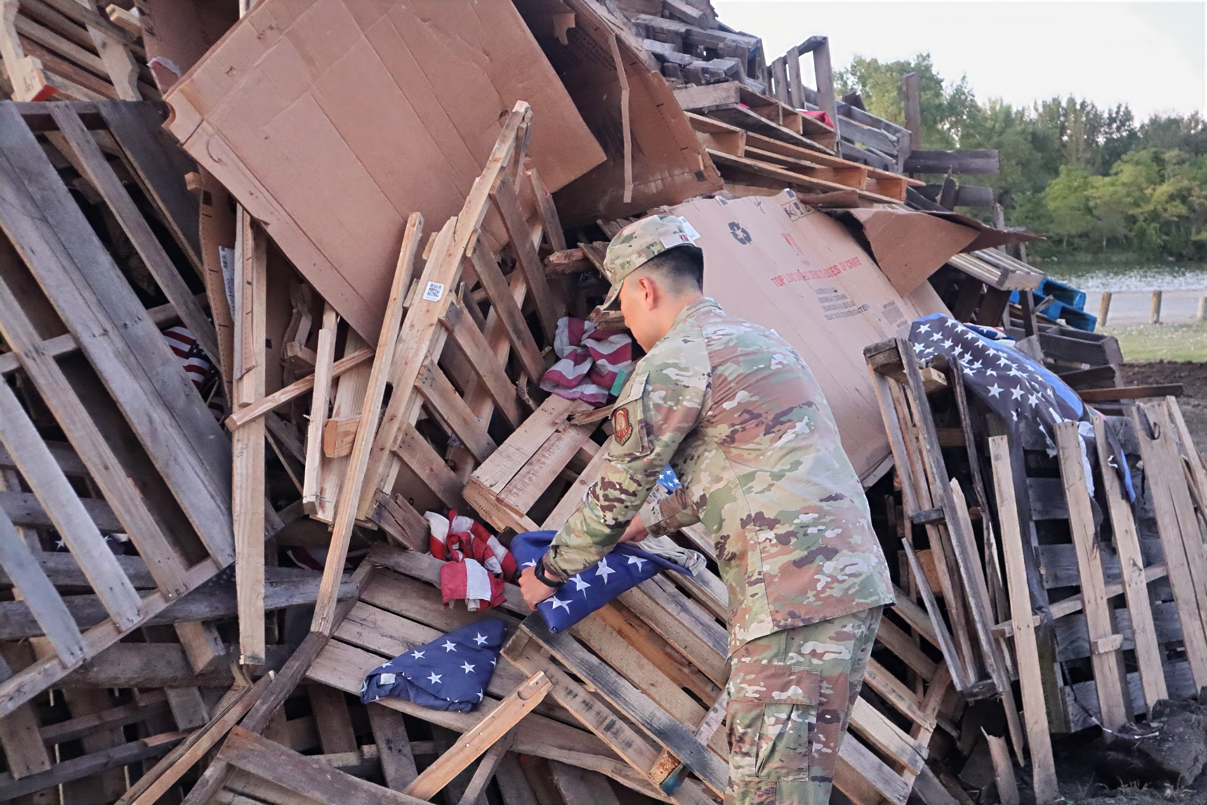 A cadet places folded United States flags onto the wooden pyre before the annual Watchfire ceremony.