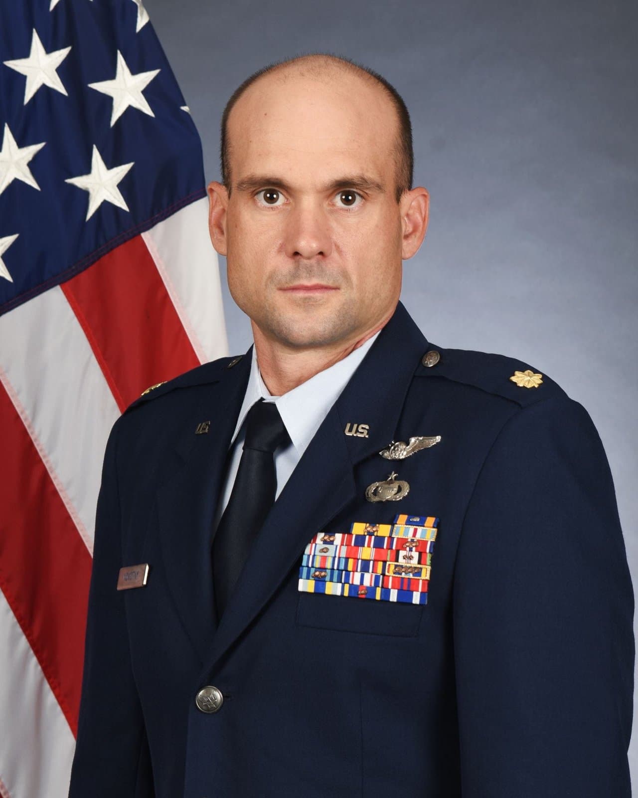 Official portrait of Maj. John J. Novotny in service dress before the United States flag.
