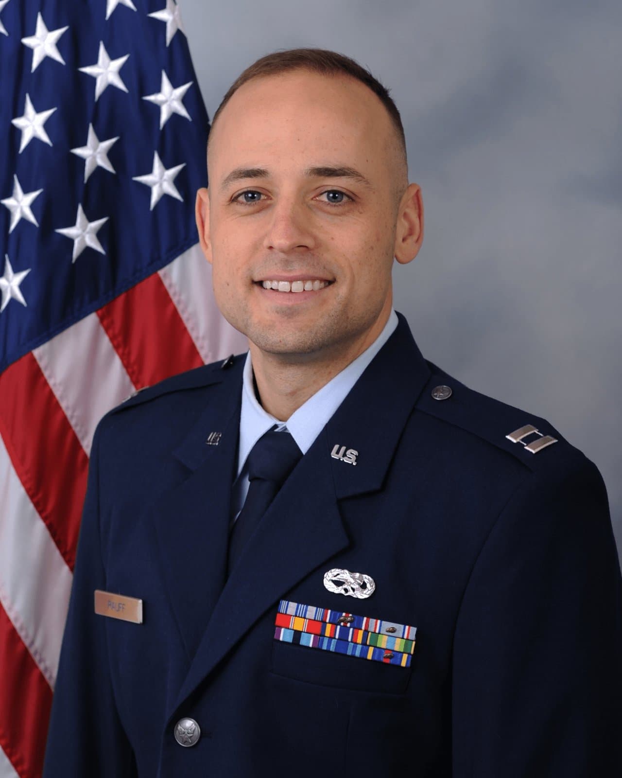 Official portrait of Capt. Robert B. Rauff in service dress before the United States flag.